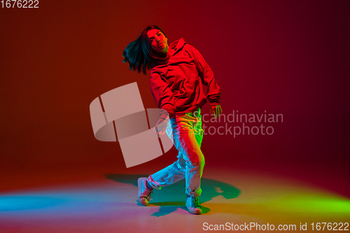 Image of Stylish sportive girl dancing hip-hop in stylish clothes on colorful background at dance hall in neon light. Youth culture, movement, style and fashion, action.