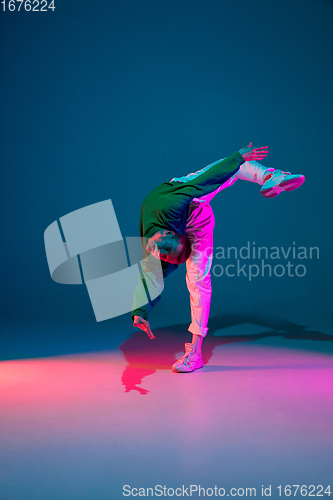 Image of Stylish sportive boy dancing hip-hop in stylish clothes on colorful background at dance hall in neon light. Youth culture, movement, style and fashion, action.