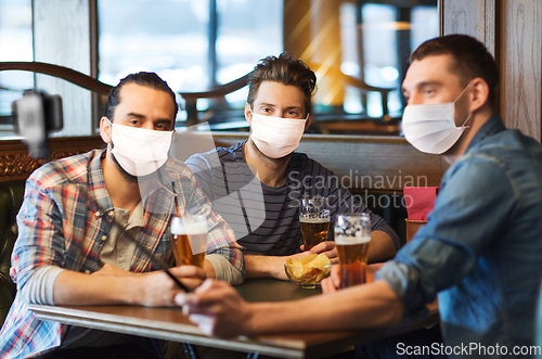 Image of men in masks take selfie and drink beer at bar