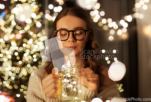 Image of woman with christmas garland lights in glass mug
