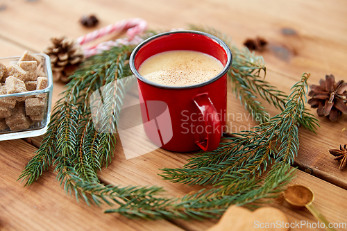 Image of red cup of eggnog, fir branches and sugar