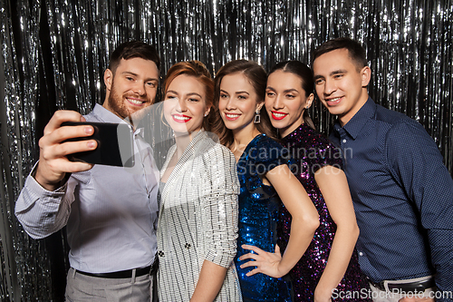 Image of happy friends taking selfie by smartphone at party