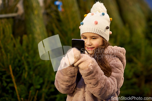 Image of girl with smartphone at christmas tree market