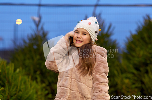 Image of girl calling on smartphone over christmas trees
