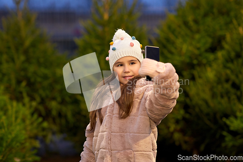 Image of little girl taking selfie at christmas tree market