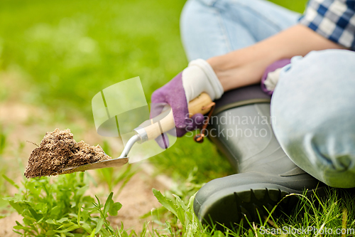 Image of hand digging flowerbed ground with garden trowel