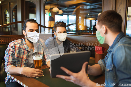 Image of men in masks with tablet pc drink beer at bar