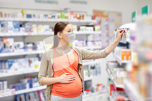 Image of pregnant woman in mask buys medicine at pharmacy