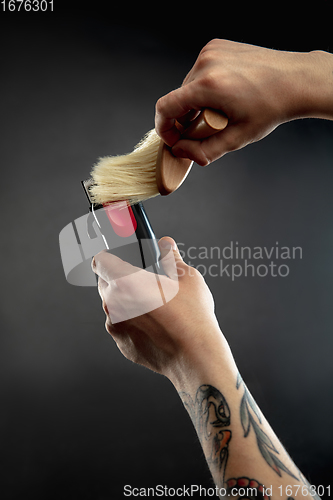 Image of Hand of male barber with equipment set isolated on black table background.