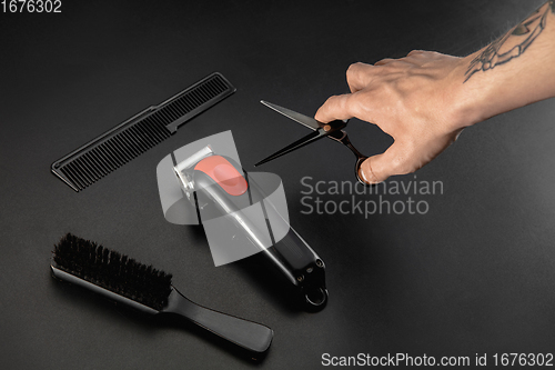 Image of Hand of male barber with equipment set isolated on black table background.