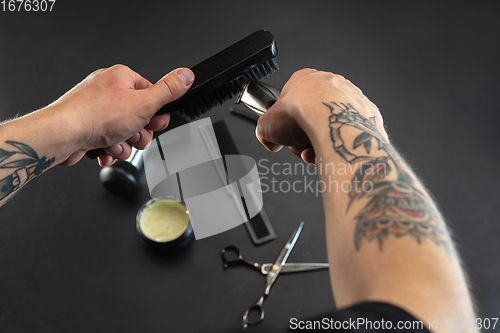 Image of Hand of male barber with equipment set isolated on black table background.