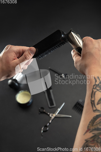 Image of Hand of male barber with equipment set isolated on black table background.