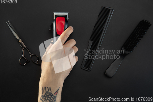 Image of Hand of male barber with equipment set isolated on black table background.