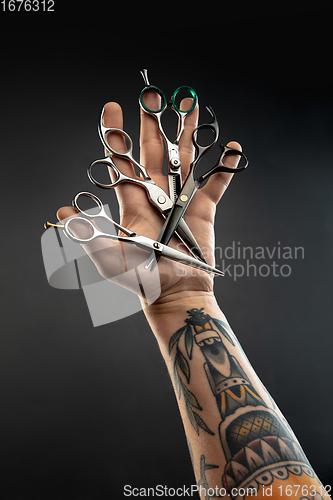 Image of Hand of male barber with equipment set isolated on black table background.