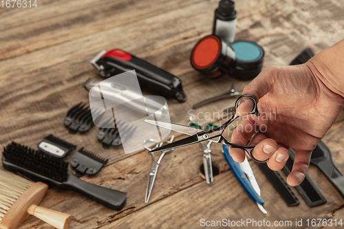 Image of Hand of male barber with equipment set isolated on wooden table background.