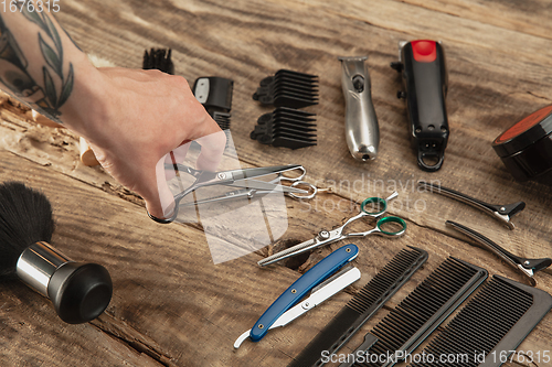 Image of Hand of male barber with equipment set isolated on wooden table background.