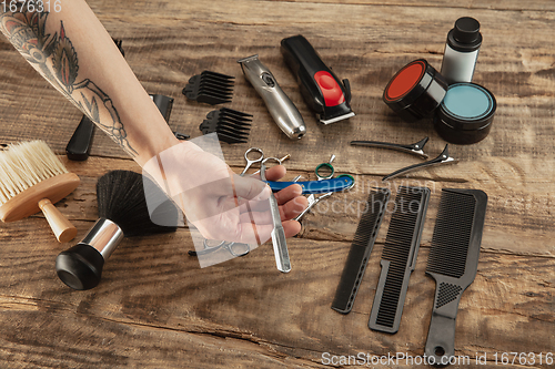 Image of Hand of male barber with equipment set isolated on wooden table background.