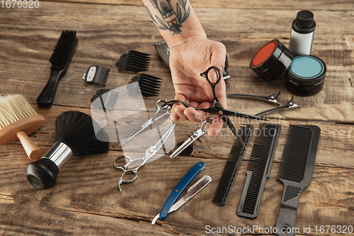 Image of Hand of male barber with equipment set isolated on wooden table background.