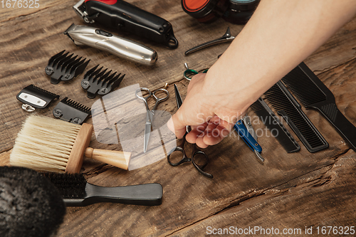 Image of Hand of male barber with equipment set isolated on wooden table background.