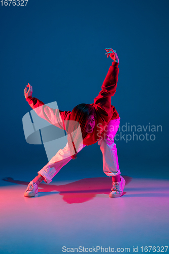 Image of Stylish sportive girl dancing hip-hop in stylish clothes on colorful background at dance hall in neon light. Youth culture, movement, style and fashion, action.