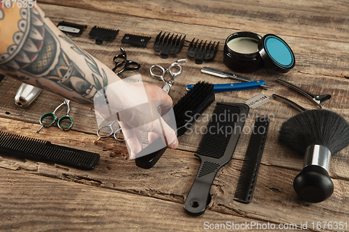 Image of Hand of male barber with equipment set isolated on wooden table background.