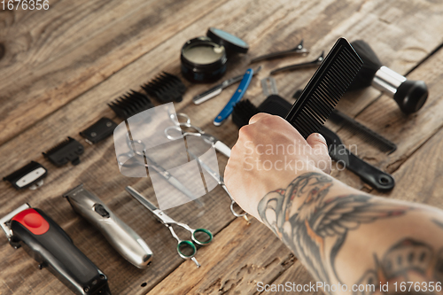 Image of Hand of male barber with equipment set isolated on wooden table background.