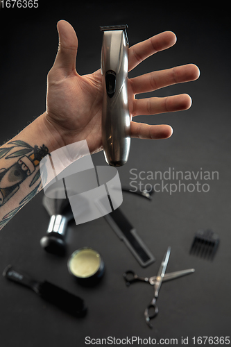 Image of Hand of male barber with equipment set isolated on black table background.