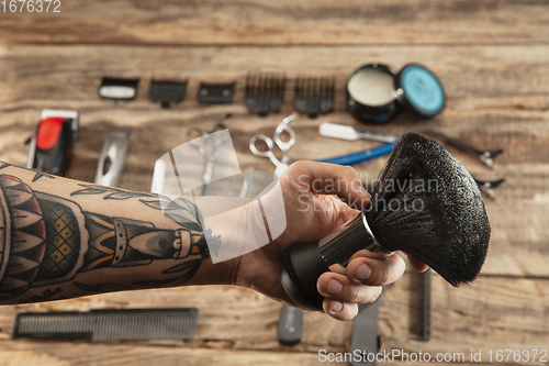 Image of Hand of male barber with equipment set isolated on wooden table background.