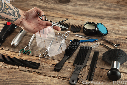 Image of Hand of male barber with equipment set isolated on wooden table background.