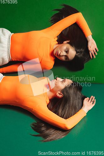 Image of Female model in sporty outfit on bicolored background with mirror. Style and beauty concept. Close up.