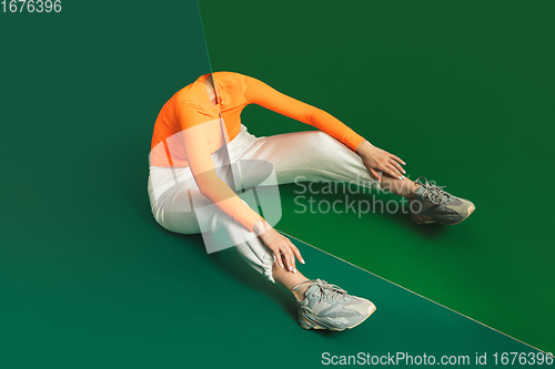 Image of Female model in sporty outfit on bicolored background with mirror. Style and beauty concept. Close up.