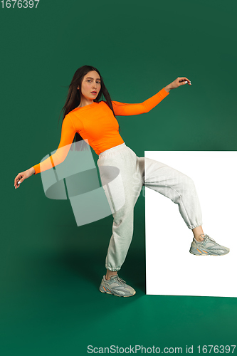 Image of Female model in sporty outfit on bicolored background with mirror. Style and beauty concept. Close up.