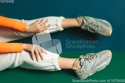 Image of Female fit legs in sporty outfit on bicolored background with mirror. Style and beauty concept. Close up.