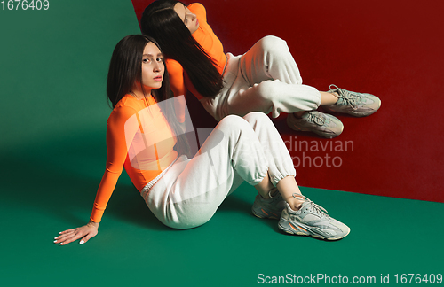 Image of Female model in sporty outfit on bicolored background with mirror. Style and beauty concept. Close up.