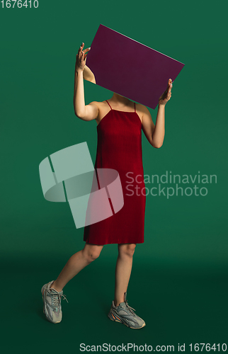 Image of Female model in red outfit on green background with mirror. Style and beauty concept. Close up.