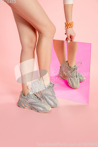 Image of Female fit legs in fashionable shoes on coral pink background with mirror. Style and beauty concept. Close up.