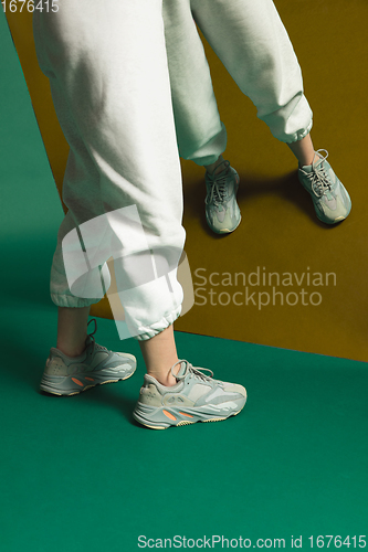 Image of Female fit legs in sporty outfit on bicolored background with mirror. Style and beauty concept. Close up.