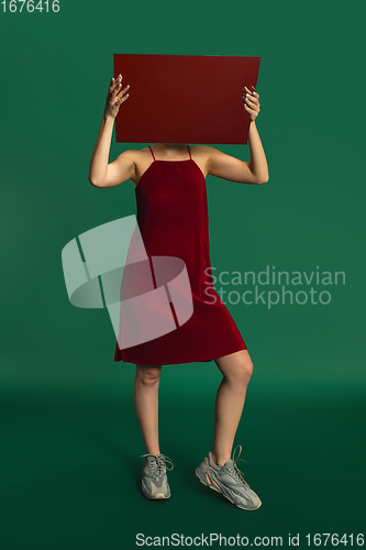 Image of Female model in red outfit on green background with mirror. Style and beauty concept. Close up.