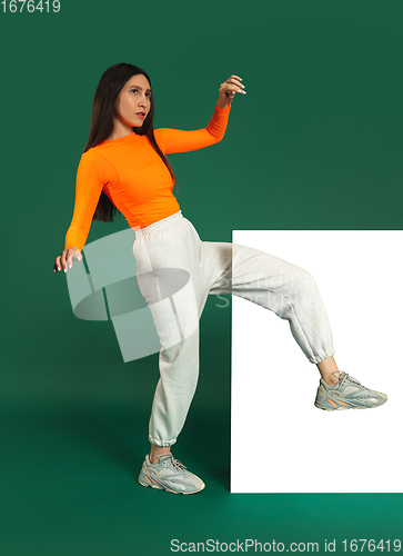 Image of Female model in sporty outfit on bicolored background with mirror. Style and beauty concept. Close up.