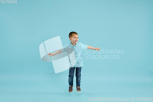 Image of Childhood and dream about big and famous future. Pretty little boy isolated on blue background