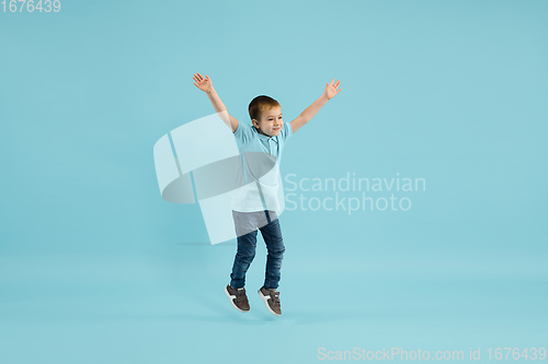 Image of Childhood and dream about big and famous future. Pretty little boy isolated on blue background