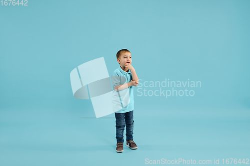Image of Childhood and dream about big and famous future. Pretty little boy isolated on blue background