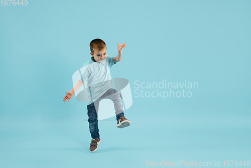 Image of Childhood and dream about big and famous future. Pretty little boy isolated on blue background