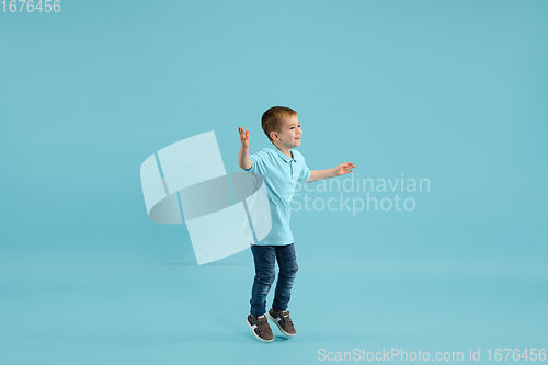 Image of Childhood and dream about big and famous future. Pretty little boy isolated on blue background