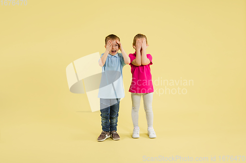 Image of Childhood and dream about big and famous future. Pretty little kids isolated on yellow studio background