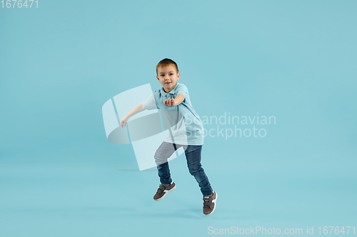 Image of Childhood and dream about big and famous future. Pretty little boy isolated on blue background