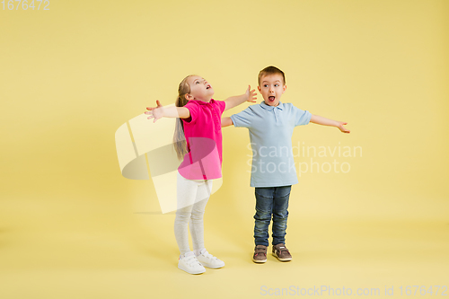 Image of Childhood and dream about big and famous future. Pretty little kids isolated on yellow studio background