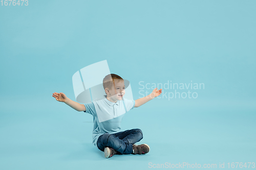 Image of Childhood and dream about big and famous future. Pretty little boy isolated on blue background