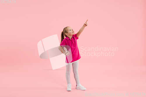 Image of Childhood and dream about big and famous future. Pretty little girl isolated on coral pink background