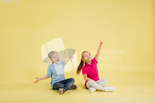 Image of Childhood and dream about big and famous future. Pretty little kids isolated on yellow studio background